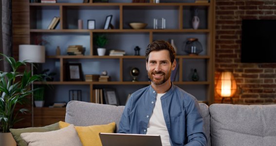 Mann sitzt auf der Couch mit einem Laptop