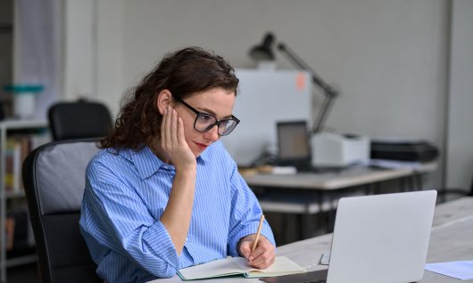 Frau sitzt und schaut auf ihrem Laptop 