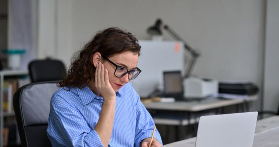 Frau sitzt und schaut auf ihrem Laptop 