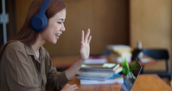 Frau trägt ein Headset und lächelt in den Laptop