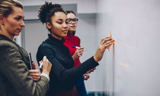 Frau klebt was auf ein Whiteboard
