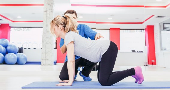 Coach unterstützt eine Frau bei einer Fitnessübung