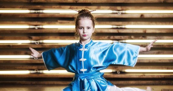 Ein junges Mädchen in Kung Fu Pose mit seitlich ausgestreckten Armen
