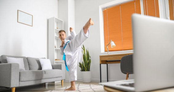 Ein Junge in Kampfpose übt eine Tritttechnik vor dem Computer 