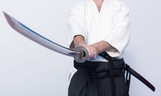 Ein Mann in japanischer Trainingskleidung hält ein Katana