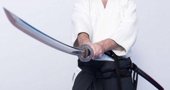 Ein Mann in japanischer Trainingskleidung hält ein Katana