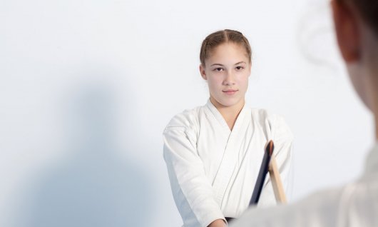 Ein Mädchen in Kampfkunst-Trainingspose mit einem Holzschwert