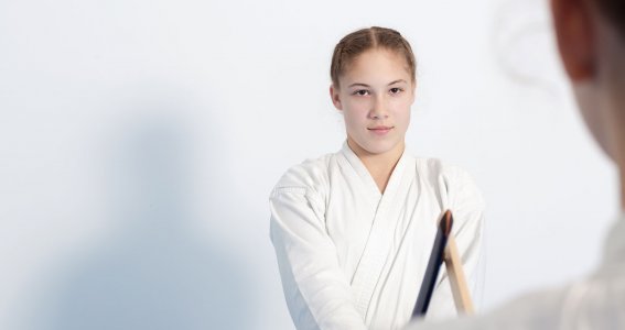 Ein Mädchen in Kampfkunst-Trainingspose mit einem Holzschwert