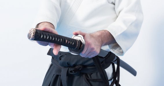 Ein Mann in Trainingskleidung zieht ein japanisches Schwert
