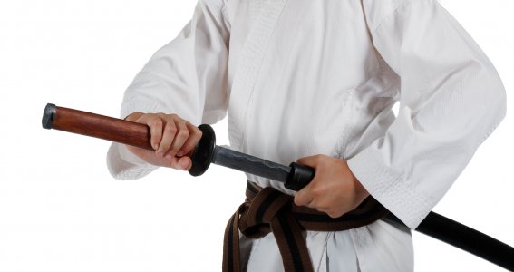 Ein Junge in Kampfsport-Trainingskleidung zieht ein japanisches Schwert