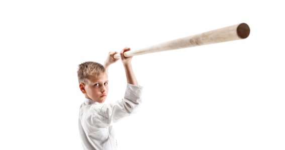 Ein Junge in Trainingskleidung hält einen Holzstock