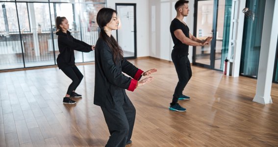 Eine Gruppe in Trainingskleidung praktiziert Tai Chi