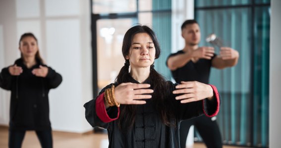 Eine Gruppe trainiert Tai Chi in schwarzer Kleidung