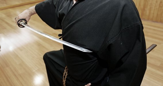 Ein Mann in schwarzer Trainingskleidung mit einem japanischen Kampfschwert