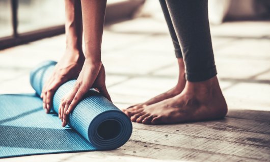 Frau rollt ihre Yogamatte zusammen