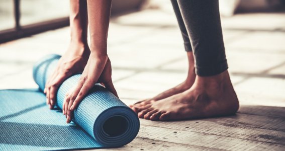 Frau rollt ihre Yogamatte zusammen