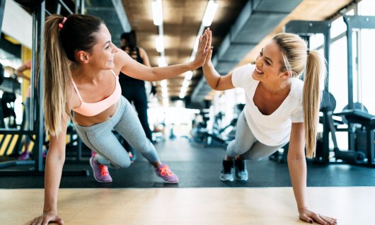 Fitnessübungen für Frauen in Köln Zwei Frauen in Liegestützposition klatschen sich ab