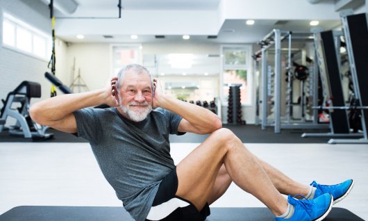 Fitnesskurs für Männer in Köln Männlicher Senior macht Sportübungen auf einer Matte