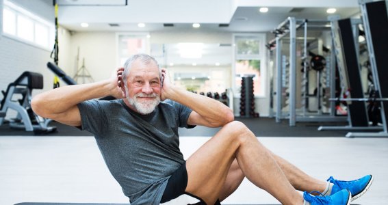 Männlicher Senior macht Sportübungen auf einer Matte