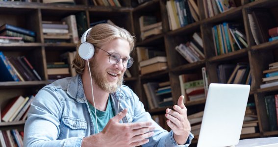 Mann sitzt mit Kopfhörern vor Laptop