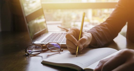 Buch neben Laptop und Brille