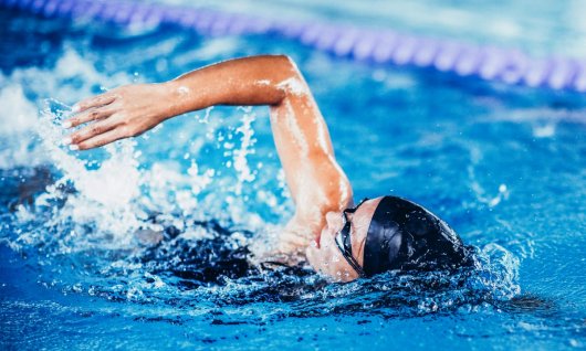 Frau lernt kraulen im Schwimmunterricht