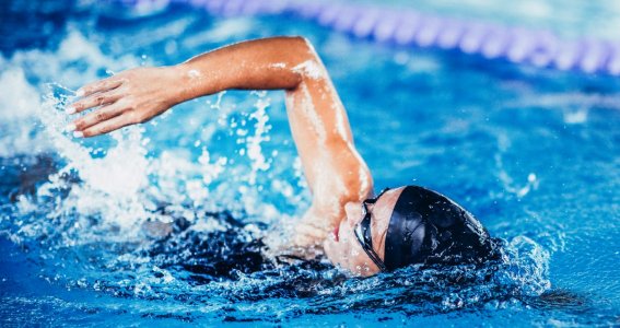 Frau lernt kraulen im Schwimmunterricht