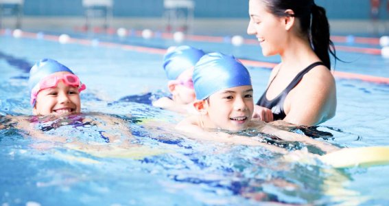 Trainerin hilft beim Schwimmen lernen