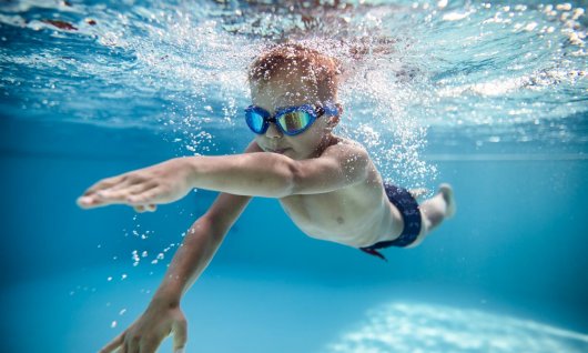 Junge lernt tauchen im Schwimmkurs
