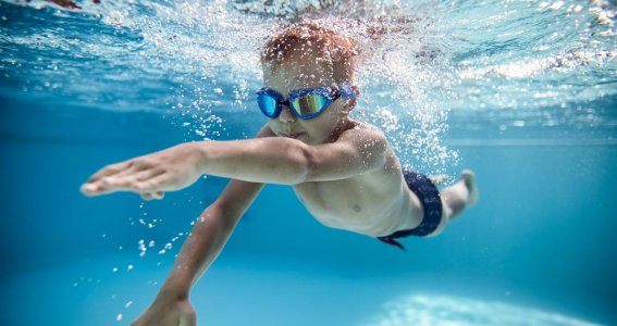 Junge lernt tauchen im Schwimmkurs