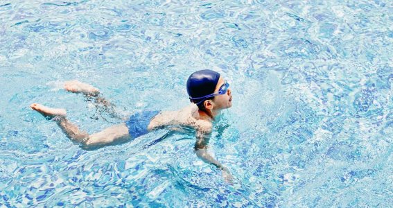 Kleiner Junge lernt im Becken schwimmen