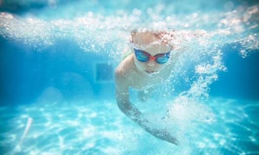 Kleiner Junge taucht beim Schwimmkurs