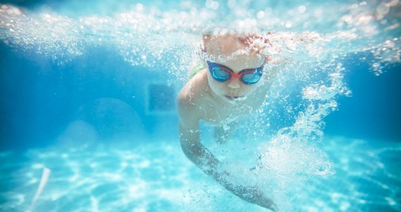 Kleiner Junge taucht beim Schwimmkurs