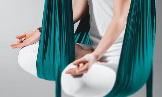 Frau meditiert in einem Yoga Tuch. 