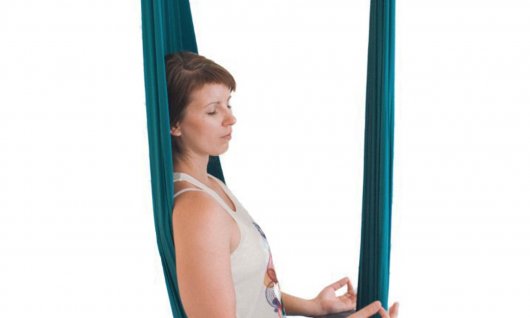 Frau meditiert im Yogatuch. 