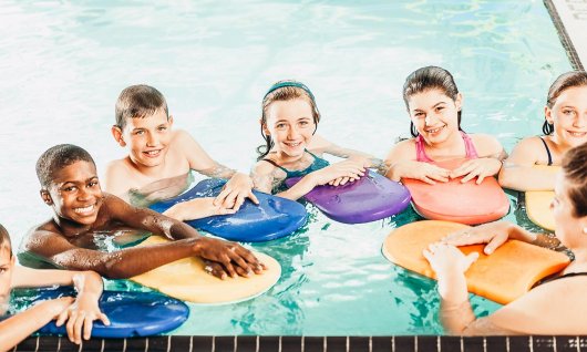 Kinder lernen mit Schwimmbrettern schwimmen