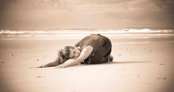 Frau entspannt sich bei Yogaübungen am Strand
