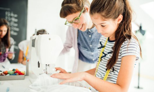 Frau und Kind nähen zusammen.