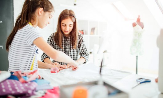 2 Mädchen nähen gemeinsam.