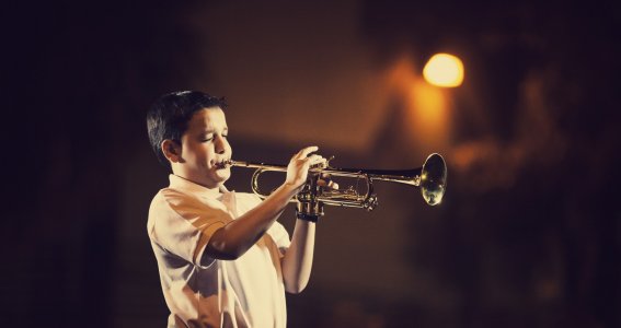 Junge spielt Trompete auf der Bühne
