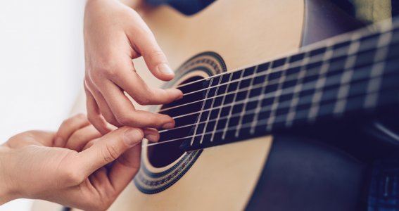 Gitarrenlehrerin bringt einen Gitarrengriff bei