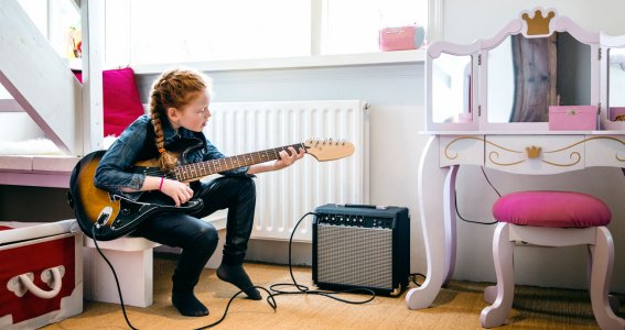 Mädchen übt für den E-Gitarrenunterricht