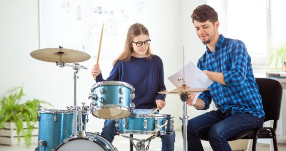Schlagzeuglehrer und Schülerin beim Musikunterricht