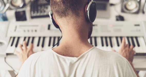 Mann mit Kopfhörern spielt Keyboard