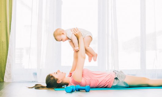 Mama macht Fitnessübungen mit ihrem Baby