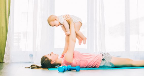 Mama macht Fitnessübungen mit ihrem Baby
