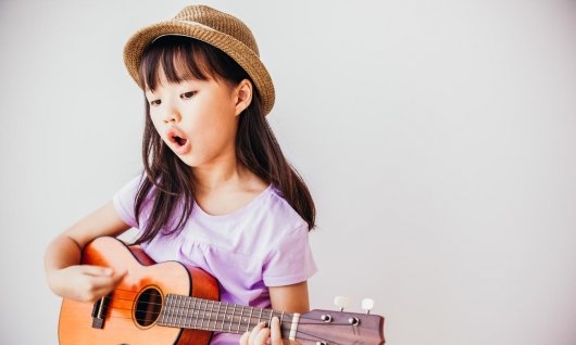 Mädchen begleitet sich beim Singen mit einer Ukulele