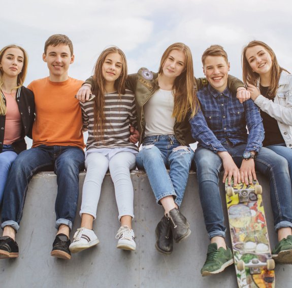 Jugendliche sitzen auf einer Mauer