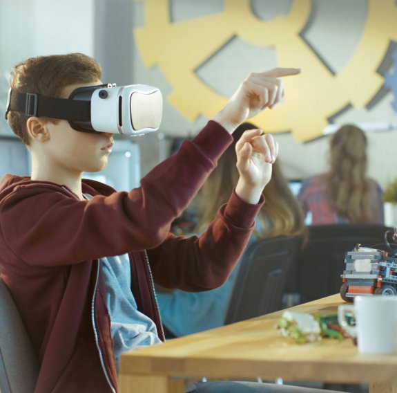 Junge sitzt mit virtual Reality Brille am Tisch