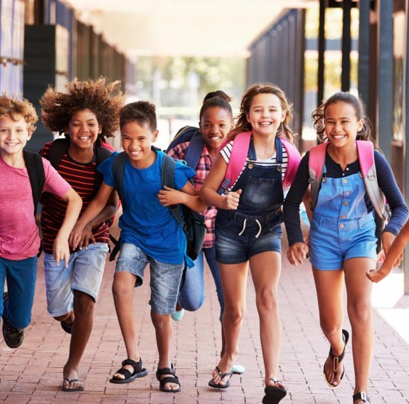 Eine Gruppe Schulkinder läuft aus der Schule hinaus